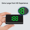 A hand holds a black portable HUD GPS speedometer with an illuminated green display.