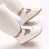 A pair of white soft non-slip baby first walker shoes worn on a foot.