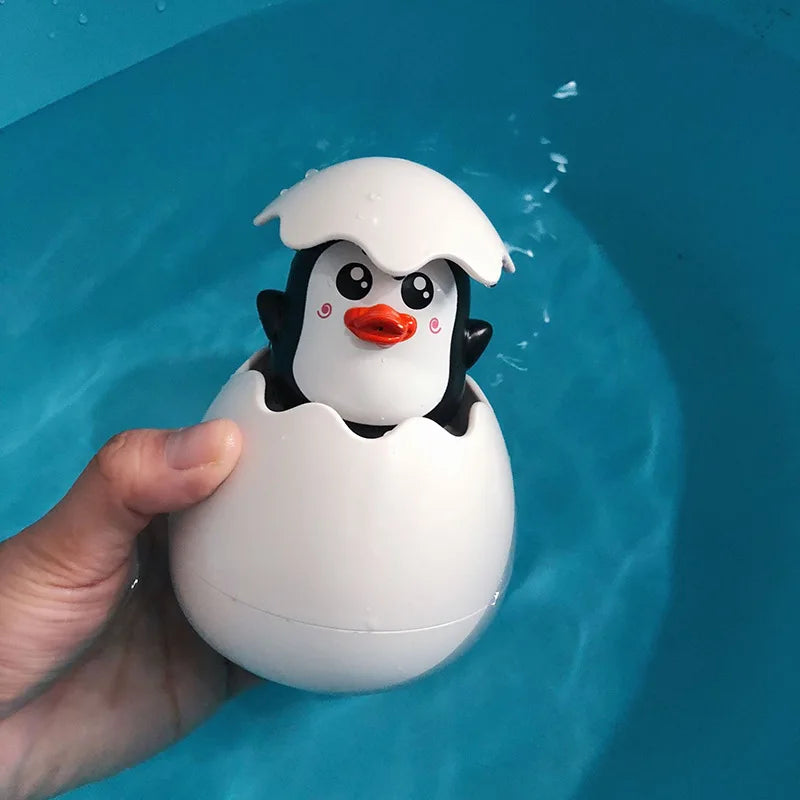 A white bath toy shaped like a penguin with an orange beak is being held over blue water.