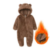 A brown fuzzy baby fleece hooded romper with a zipper is shown next to a small flame.