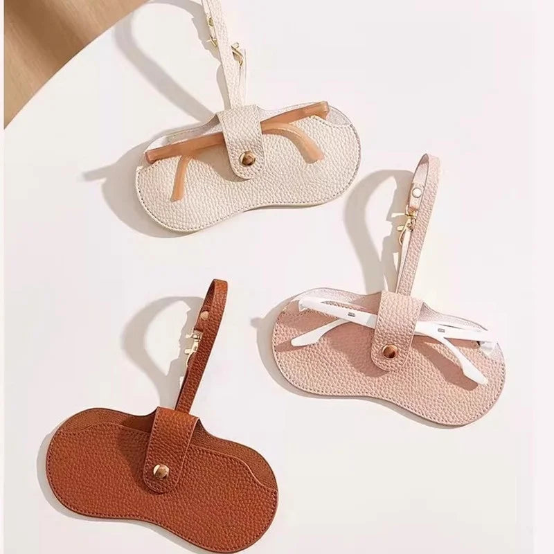 Kaksi ohutta magneettista nahkaista silmälasikoteloa beige- ja ruskeanvärisinä, naruilla