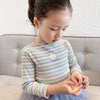 A young girl wearing a colorful striped t-shirt with a flower print and a sheer gray skirt.