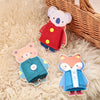 Two wooden Montessori busy board figures, a bear and a koala, are displayed on a fluffy surface next to a wicker basket.