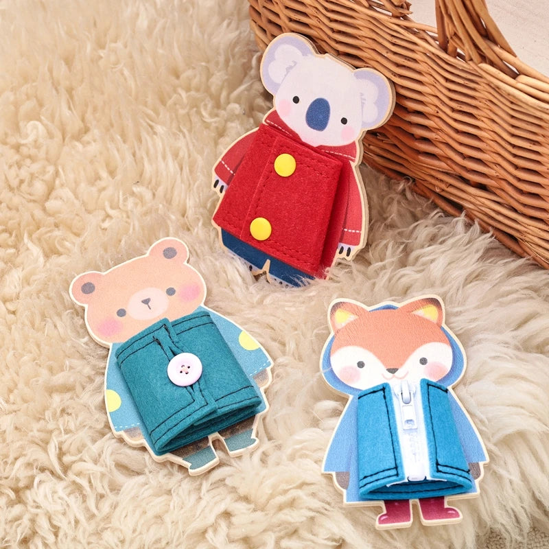 Two wooden Montessori busy board figures, a bear and a koala, are displayed on a fluffy surface next to a wicker basket.