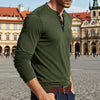 A man wearing an olive green long-sleeve casual shirt with a collar and chest pocket standing in a European square.