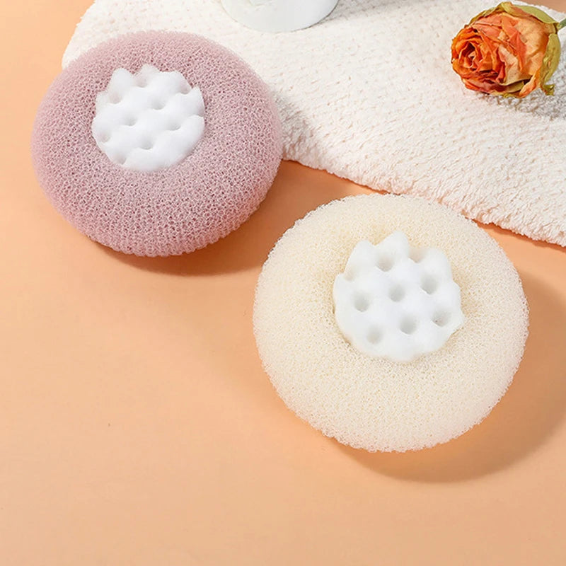 A pink and white bath sponge with a sunflower design is shown next to a peach-colored towel.