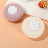 A pink and white bath sponge with a sunflower design is shown next to a peach-colored towel.
