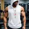 A muscular man wearing a white hooded tank top stands in a gym setting.
