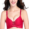 Kvinde modellerer en rød sømløs push-up bralette med justerbare stropper og snørring.