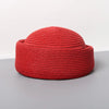 A bright red woven straw pillbox sun hat with a wide brim shown against a neutral background.