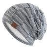 A gray and white knit slouchy beanie with a textured pattern and a white sherpa lining.