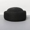 A black woven straw pillbox sun hat with a wide brim shown against a light gray background.