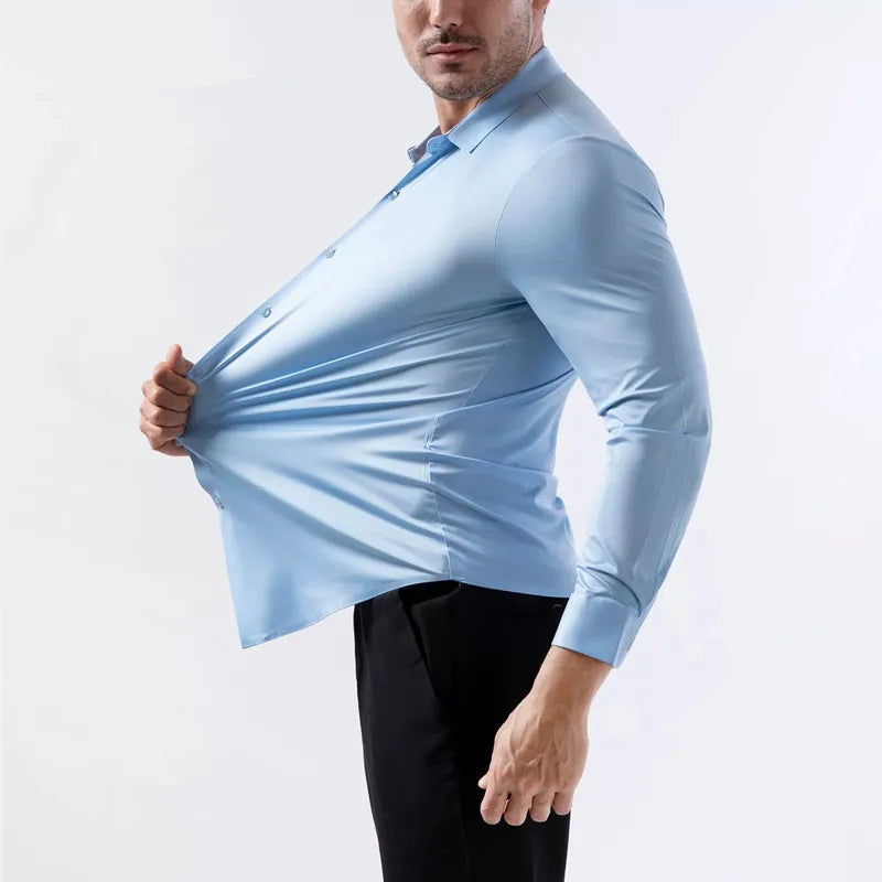 Hombre con camisa azul claro sin planchar y pantalones negros, de pecho hacia arriba.