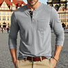 A man wearing a gray long-sleeve casual shirt with a chest pocket and brown belt, standing outdoors.