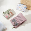 A pink floral print women's wallet with a zipper and card slots is shown next to a light blue floral print wallet.