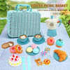 A blue wicker picnic basket filled with pretend play food items like donuts, pastries, and fruit on a checkered tablecloth.