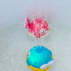 A pink fish and a blue whale toy are being sprayed with water in a bathtub.