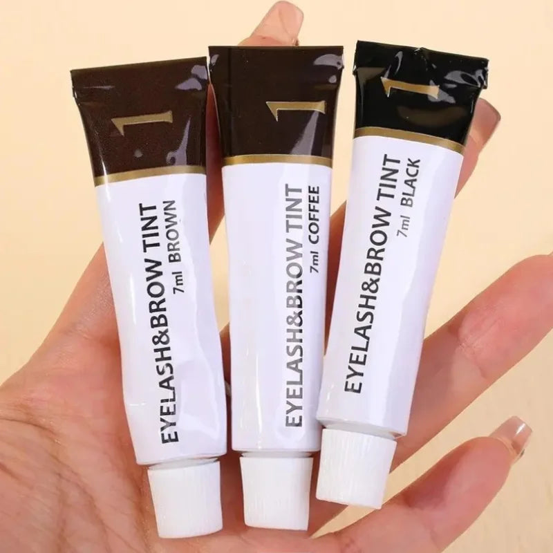 A hand holds a tube of Eyelash & Brow Tint, featuring brown tint and black tint options.