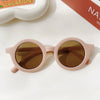 A pair of light pink sunglasses with brown tinted lenses resting on a white surface.