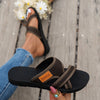 A close-up of women's brown breathable mesh flat sandals on a person's foot, set against a wooden surface.