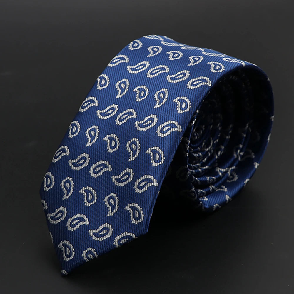 Una corbata azul oscuro con diseño de cachemira blanco, enrollada.