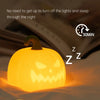 A glowing orange pumpkin silicone touch night light is shown illuminating a surface, demonstrating its two functions.