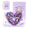 A purple pop-up card featuring a heart shape decorated with colorful flowers and butterflies.