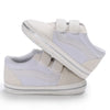 A pair of white canvas baby sneakers with a light gray sole and white laces.