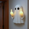 A white glowing resin ghost lamp with hands making a sassy gesture mounted on a wall.