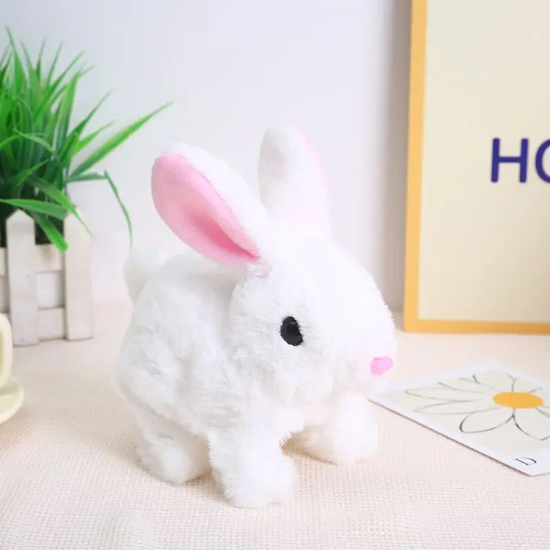 A white and pink interactive walking bunny plush toy sitting on a light surface.