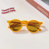 A pair of bright yellow sunglasses with amber lenses resting on a white surface.