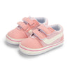 Pink and white striped canvas baby sneakers with anti-slip soles shown from above