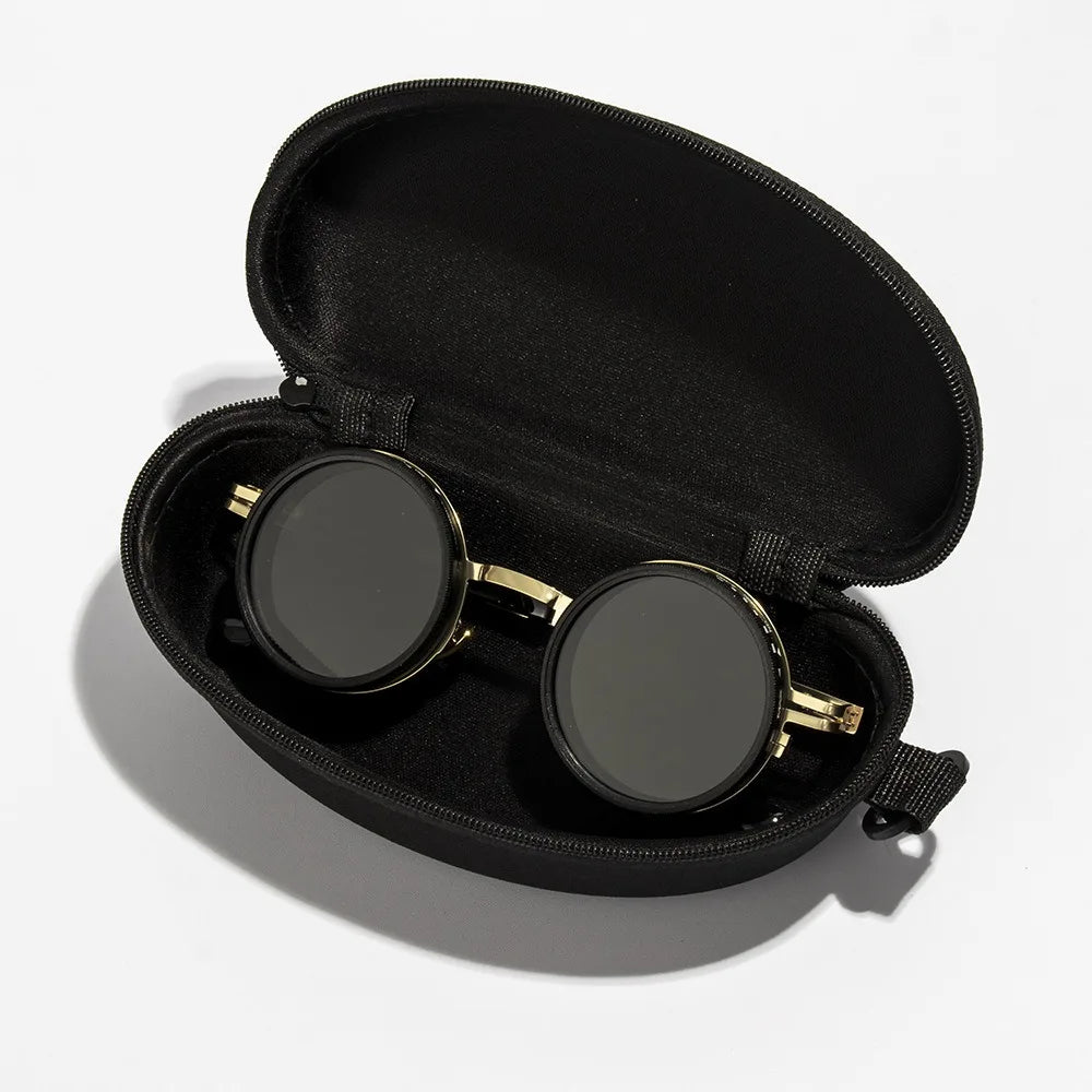 A pair of gold-framed sunglasses with dark lenses resting inside a black velvet storage case.