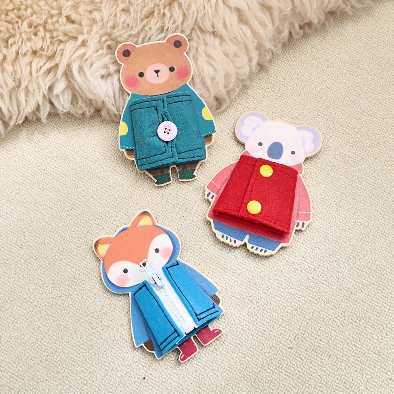 Three wooden Montessori busy board figures of animals dressed in clothing, including a bear, a elephant, and a fox.