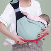 A woman is holding a soft cotton baby ring sling carrier against her chest.