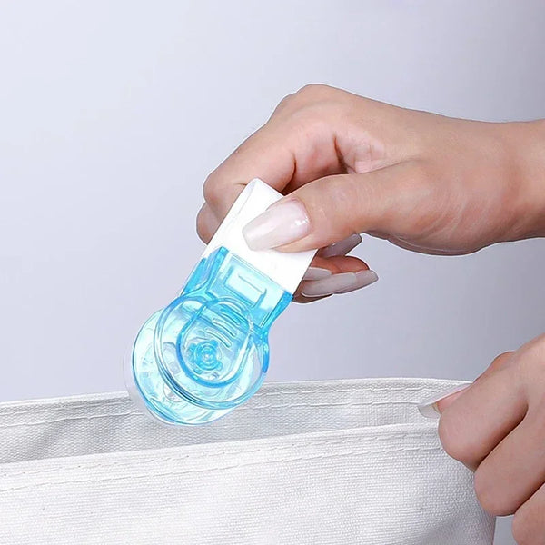 A hand is opening a clear blue portable pill blister pack opener with a white cap and storage compartment.