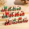 A collection of miniature red and green Christmas train decorations featuring Santa figures and festive scenery on a wooden s
