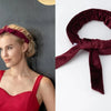 A woman wearing a red top and a maroon velvet heatless curling rod headband is shown alongside the product.