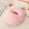 A pink, fluffy USB heated foot warmer with a soft fleece cover resting on a white textured surface.