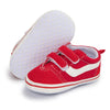 A pair of red and white canvas baby sneakers with a white anti-slip sole.