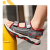A close-up of a pair of gray and red boys' breathable summer sport sandals being worn on a foot.