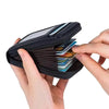 A hand holds a black compact zipper card holder with multiple cards inside.
