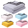 A stack of various colored breathable cooling throw blankets including gray, light blue, yellow, and pink.