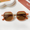 A pair of brown sunglasses with a light teal accent frame resting on a white surface.