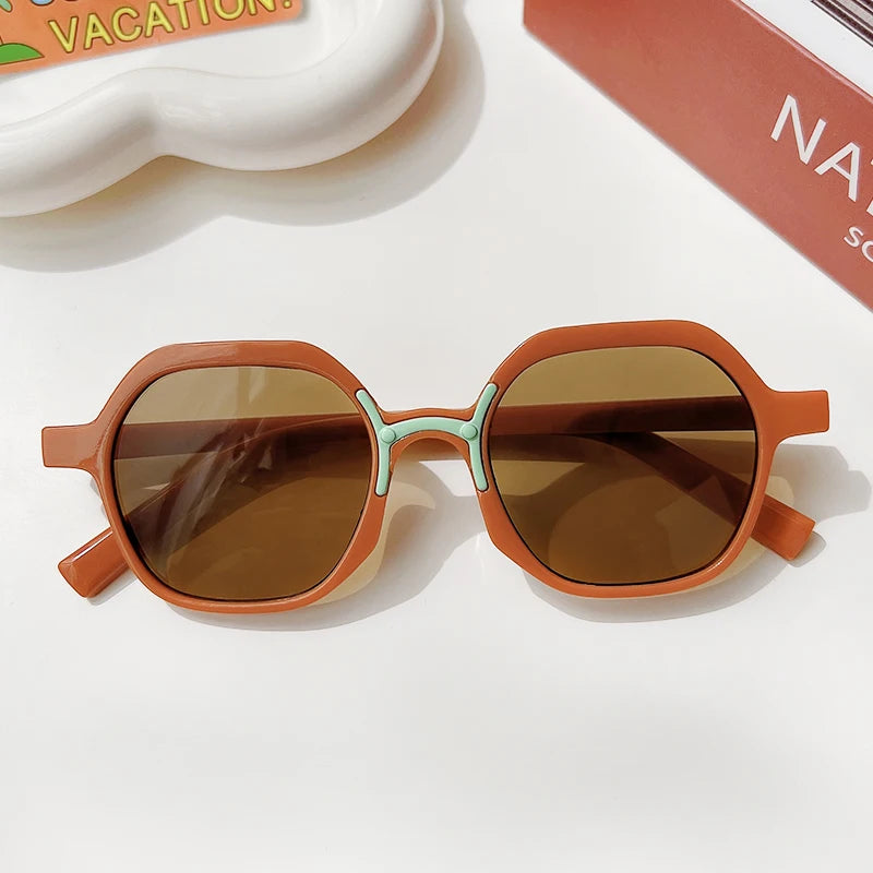 A pair of brown sunglasses with a light teal accent frame resting on a white surface.