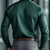 A man wearing a dark green long-sleeve formal shirt and gray trousers, viewed from the back.