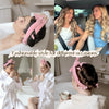 A woman is shown using a pink heatless overnight curling headband with a satin finish for styling hair.