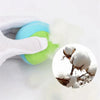 A hand is squeezing a bright blue and lime green sticky dodgeball vest set, with white fluff or cotton visible nearby.