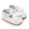 A pair of white baby first walker shoes with lace-up straps and ribbon bows