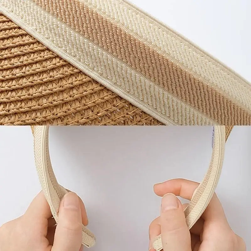 A close-up view of a woven straw sun hat with a wide brim being held by hands.